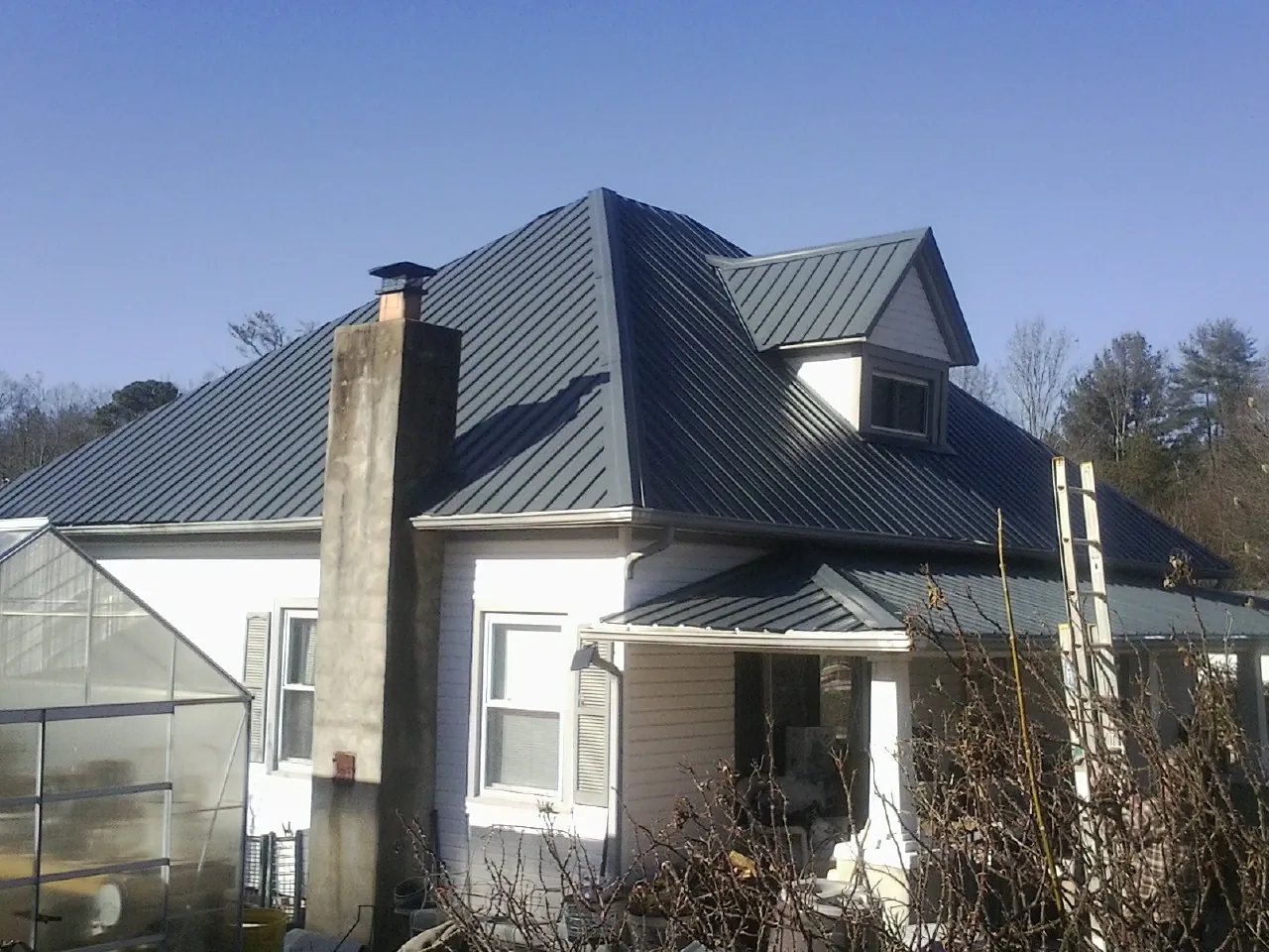 Dark blue standing seam metal roof on a white farmhouse with dormer — Slate & Tile Roof Repair by Roofing Brothers in Benicia