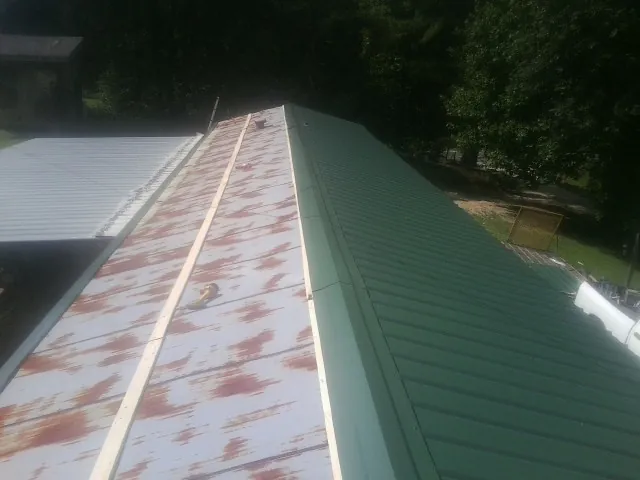 Old rusted panels beside newly installed green metal roofing — Wind Damage Roof Repair by Roofing Brothers in Benicia