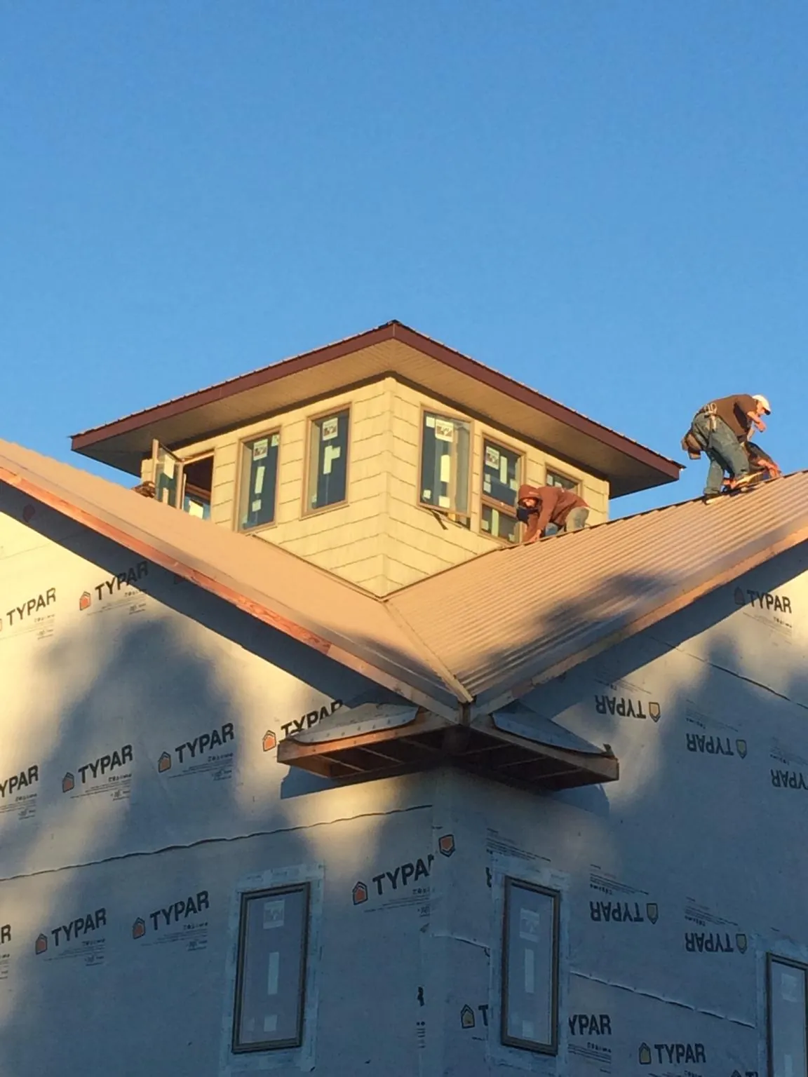Roofers working around a rooftop cupola on a new metal roof at sunset — Roof Waterproofing in Benicia by Roofing Brothers